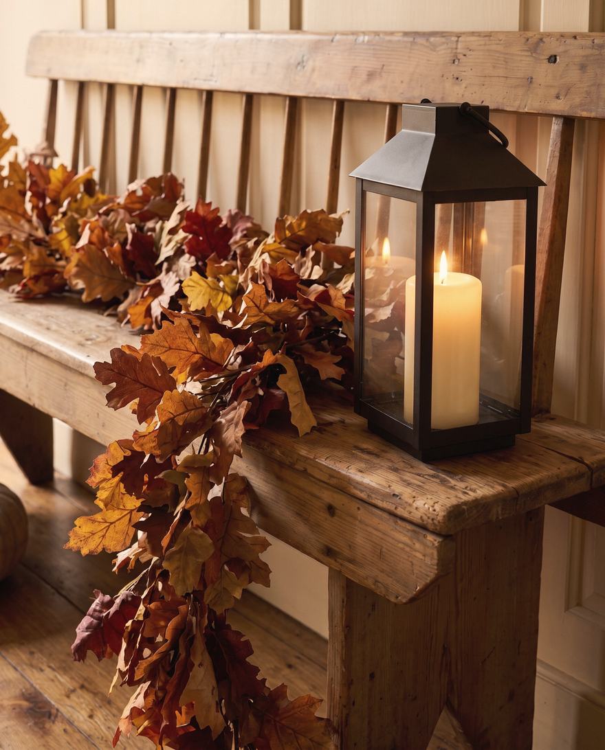 The lantern at the end of the bench, under a fall of leaves.